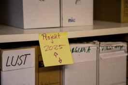 Foto von einem weißen Regal, in dem sechs Papierschuber ausschnitthaft zu sehen sind. Der Schuber unten links ist mit