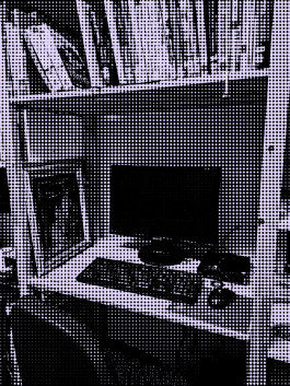 Ein Desktop-PC wird umrahmt von Bücherregalen aus Holz. Davor steht ein Bürostuhl.